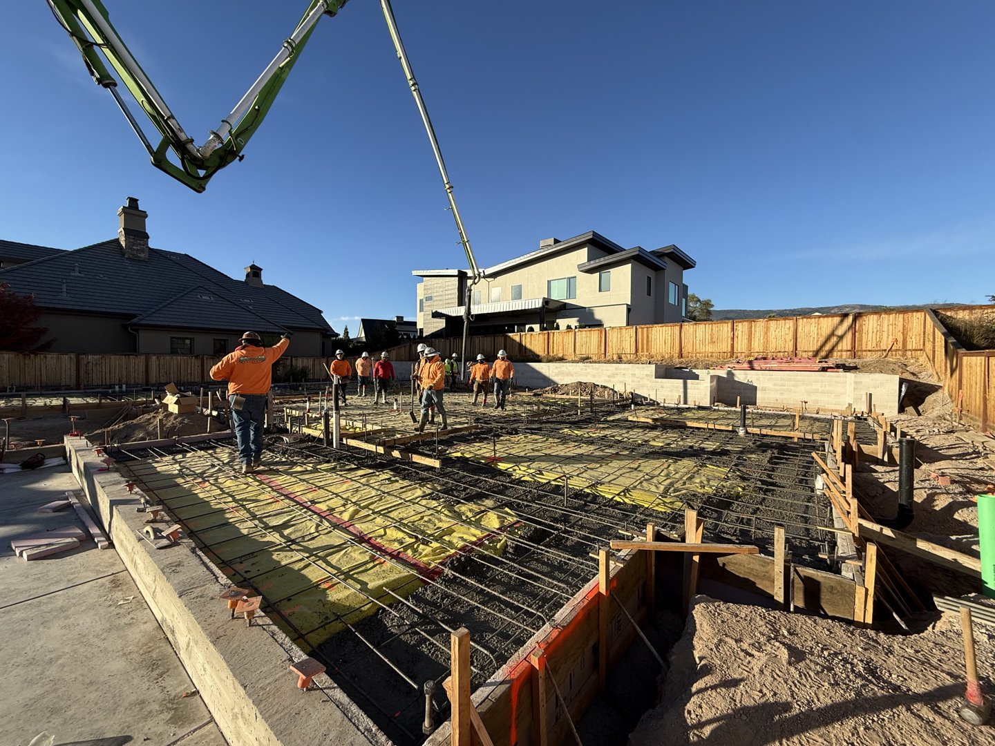 Concrete pump boom positioned over the reinforced slab, crew staged to begin the pour