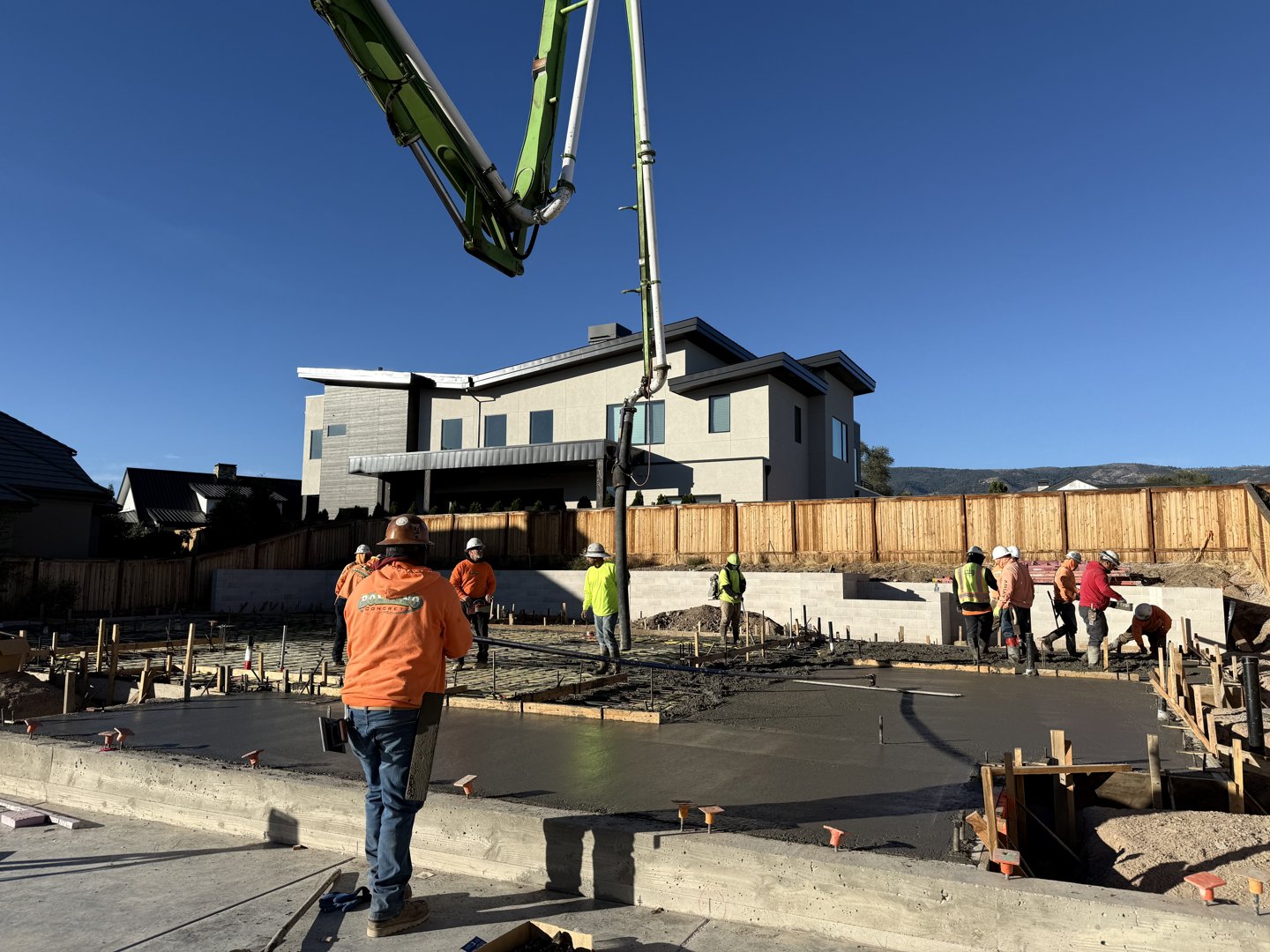 Pump hose placing concrete as the crew works across the slab